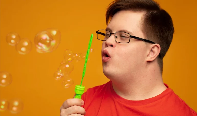 Menino com síndrome de down soprando bolhas de sabão